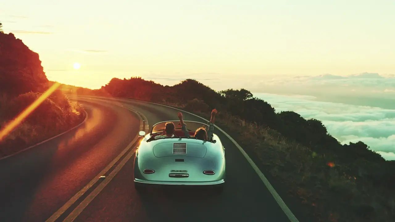 Un’auto d’epoca cabriolet su una strada di montagna al tramonto